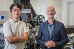 Hyeon Han and Stuart Parkin in front of the pulsed laser deposition system (Pascal Co., Ltd., Ibaraki, Japan) at the Max Planck Institute of Microstructure Physics that was used to create the single crystalline T-Nb2O5 films used in the study.